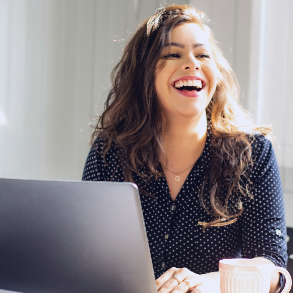 woman laughing while working with laptop